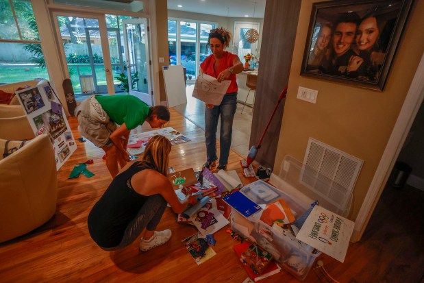 Members of the Boonstoppel family and a friend look through Harrison's old drawings while they create a display in his memory at the Boonstoppels' Tampa home on Monday.