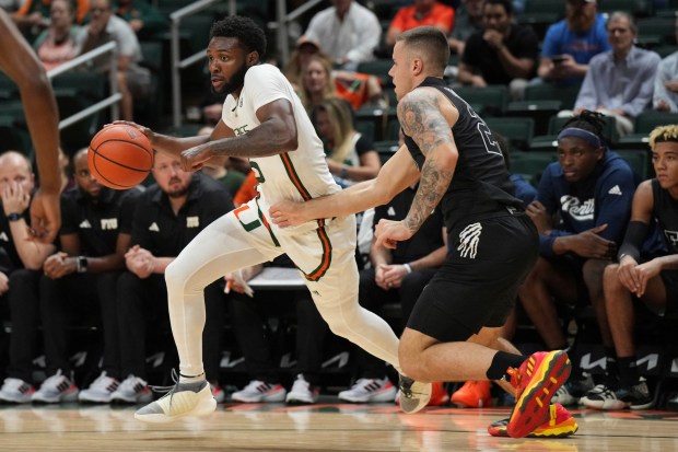 Miami guard Wooga Poplar looks for room as Florida International guard Arturo Dean defends during the first half of an NCAA college basketball game, Monday, Nov. 13, 2023, in Coral Gables, Fla. (AP Photo/Jim Rassol)